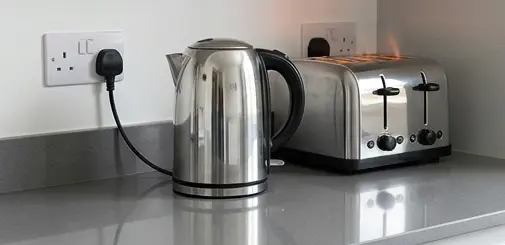 UK kettle and toaster on a kitchen worktop — common high-wattage appliances that can trip a circuit breaker when used together